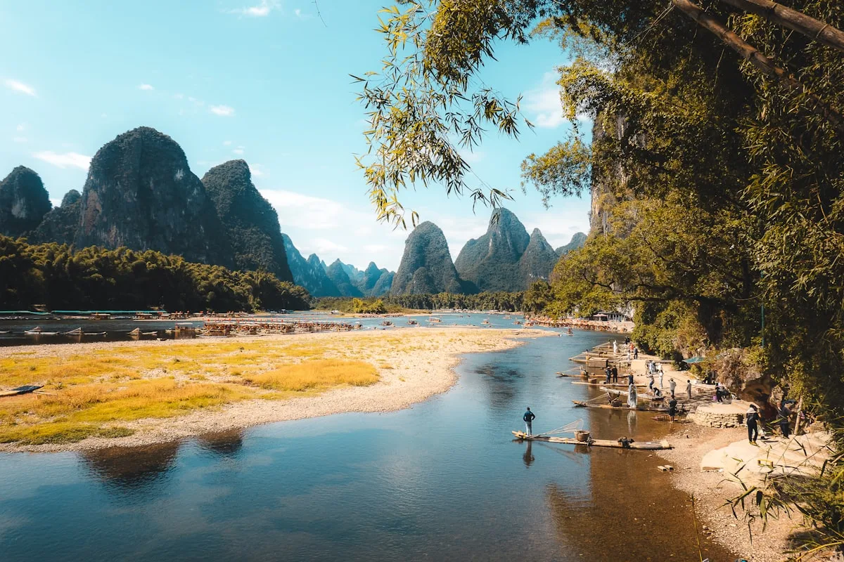 Karst mountains rise above a tranquil river with bamboo trees near Yangshuo