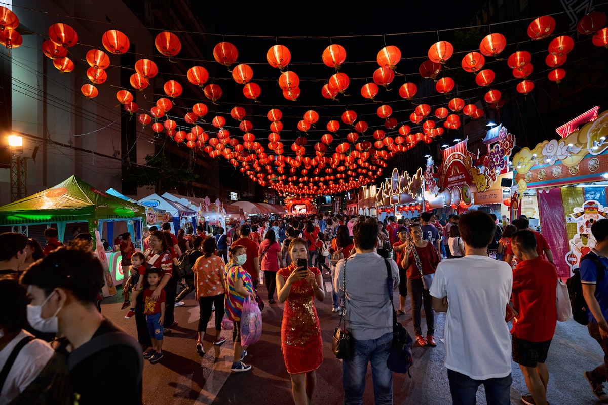 A crowd of people walking down a street under red lanterns during Chinese Spring Festival celebration