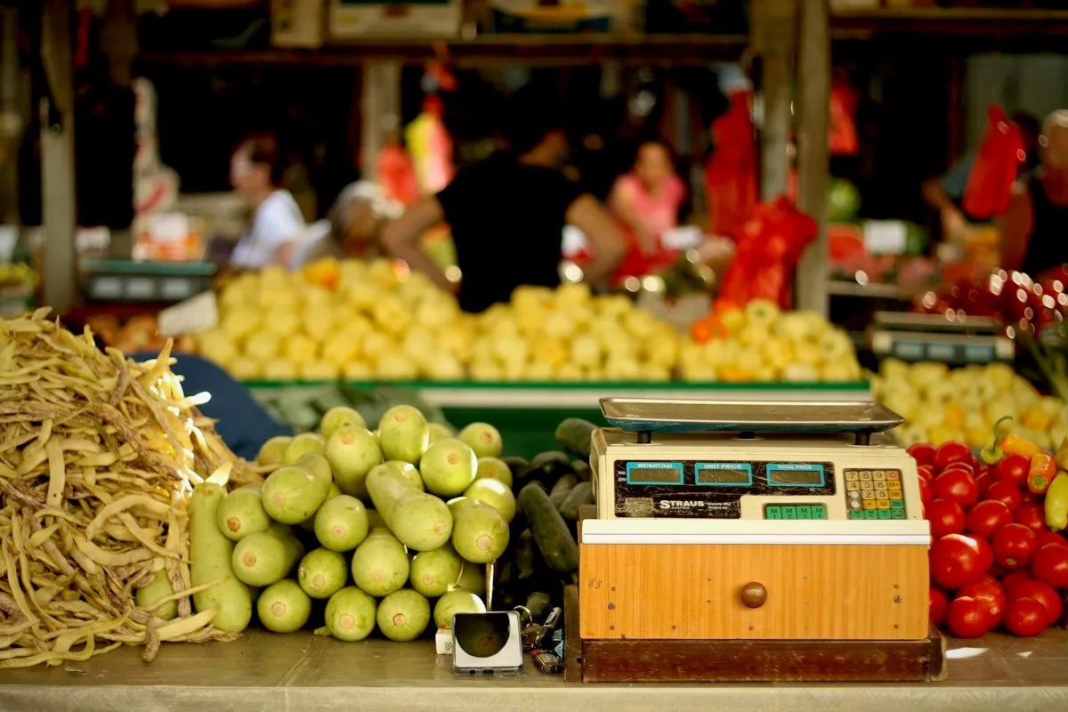A vegetable stall in a Chinese market with tomatoes, greens and an old electronic scale
