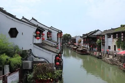 White and red boat floating on a peaceful canal in Suzhou ancient water town