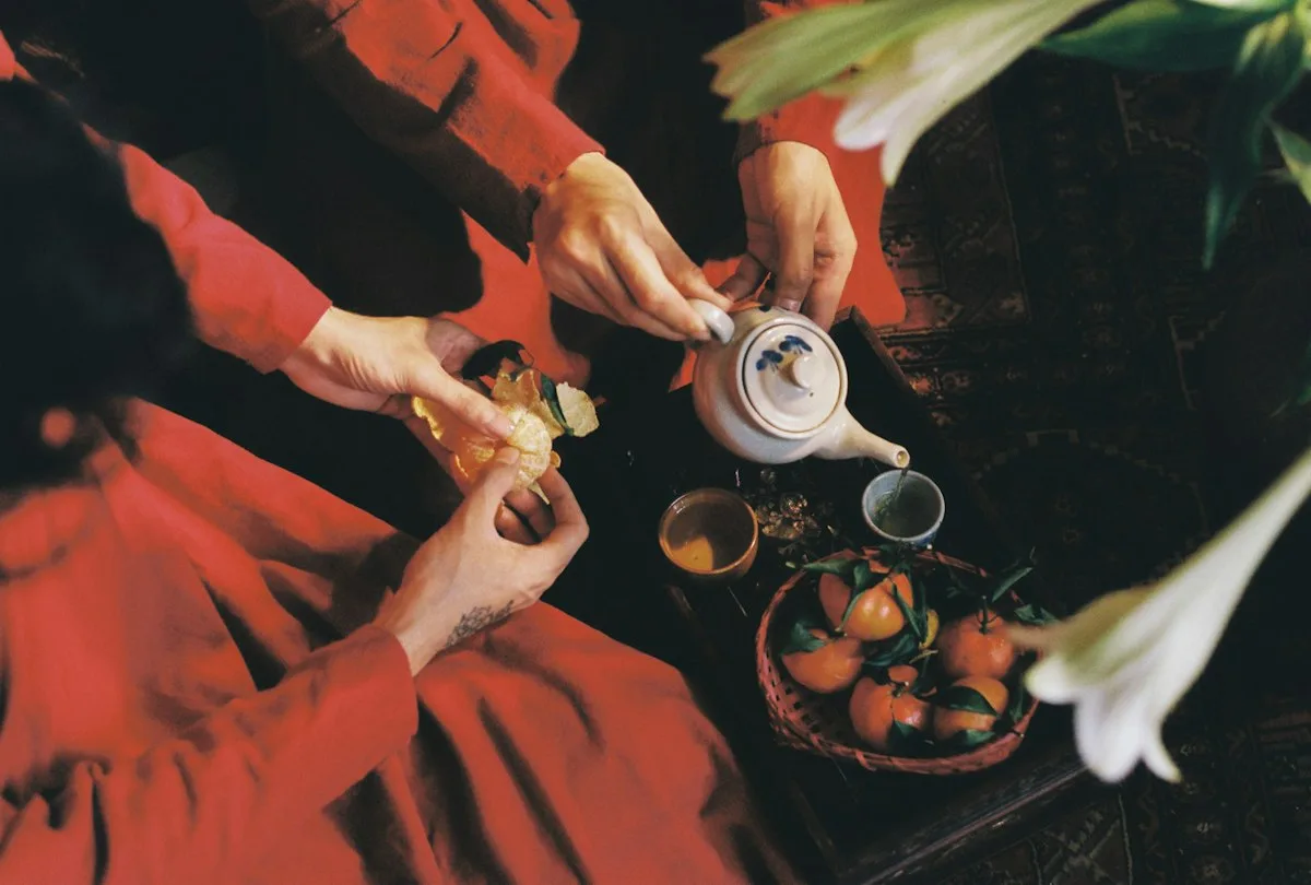 Dos personas con traje tradicional rojo sirviendo té en una mesa de ceremonia del té