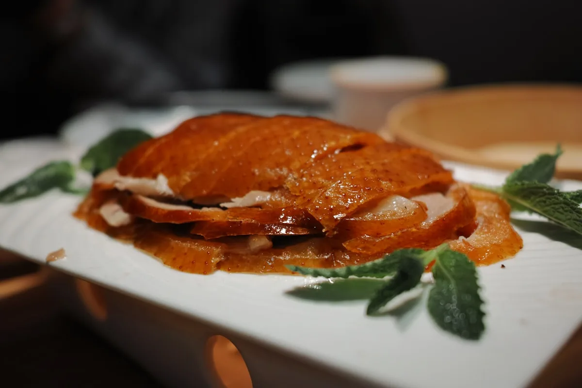 Crispy Peking duck — lacquered mahogany skin, sliced and plated, the defining dish of Beijing's imperial food culture