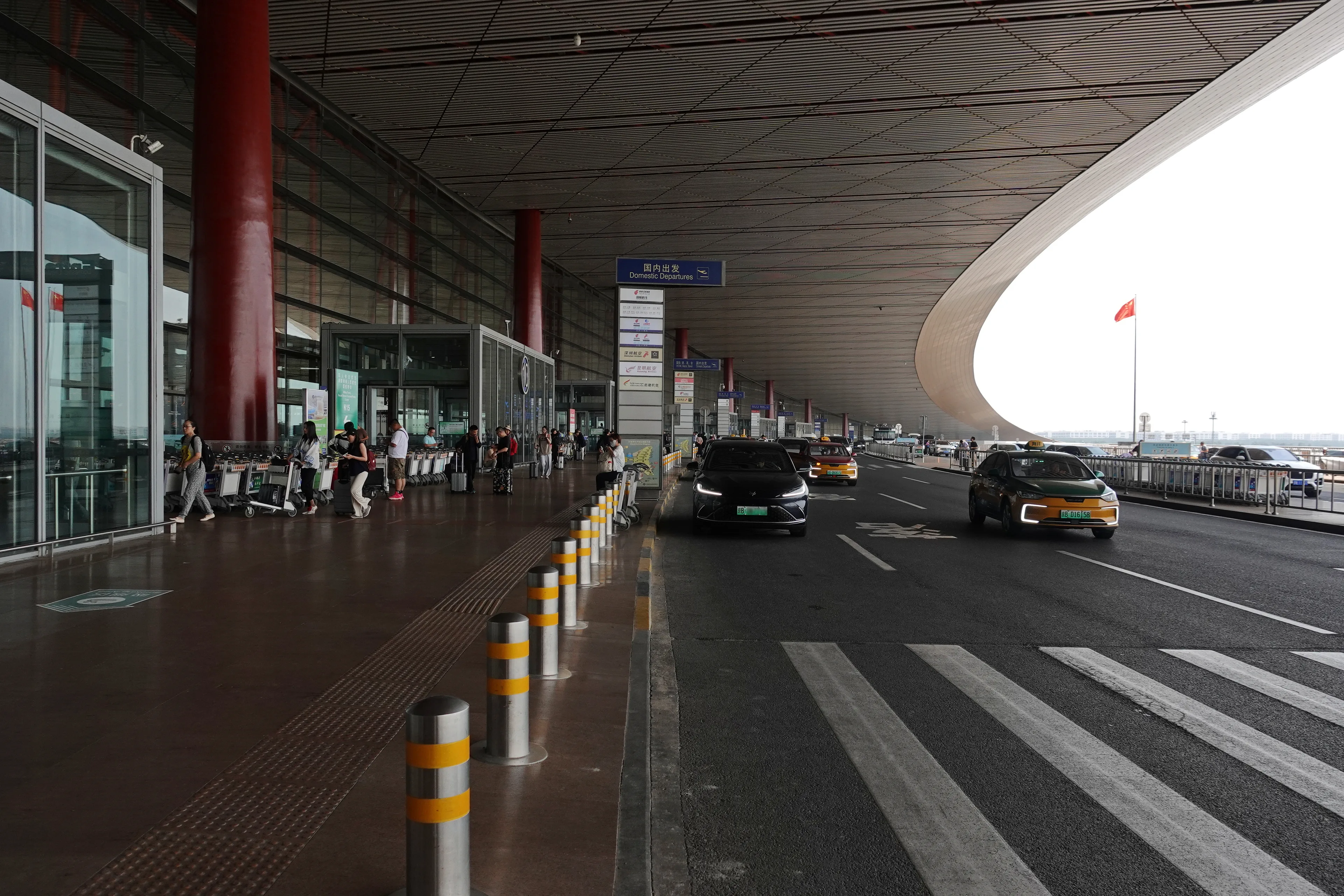 Departure curbside at Beijing Capital International Airport Terminal 3 with taxis and luggage carts (Photo: 颐园居 via Wikimedia Commons)