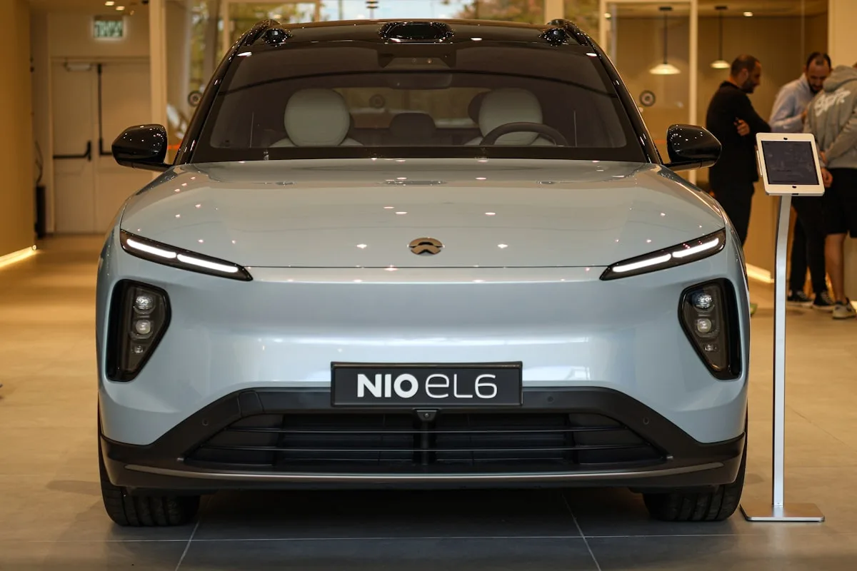 Visitantes observando un SUV eléctrico NIO azul claro expuesto en un salón de exposición