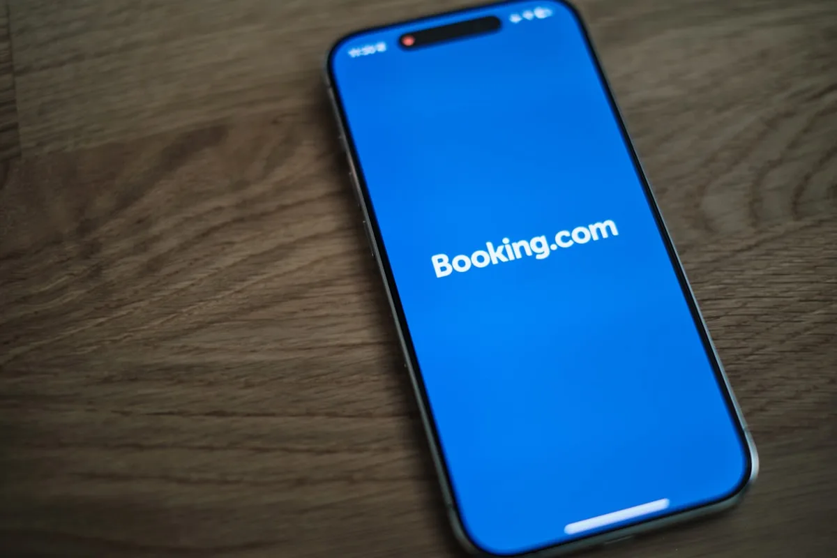 Un smartphone affichant l'application Booking.com posé sur une table en bois