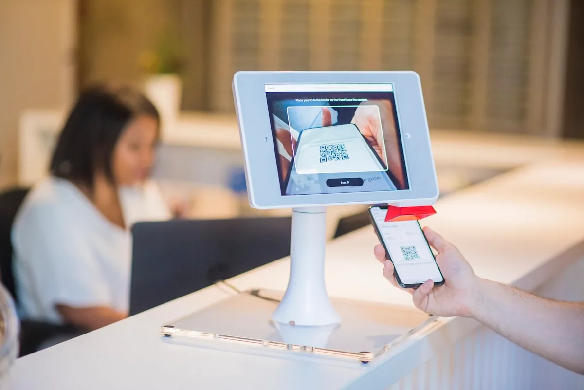 Un voyageur scannant un QR code sur une tablette à la réception d'un hôtel pour s'enregistrer
