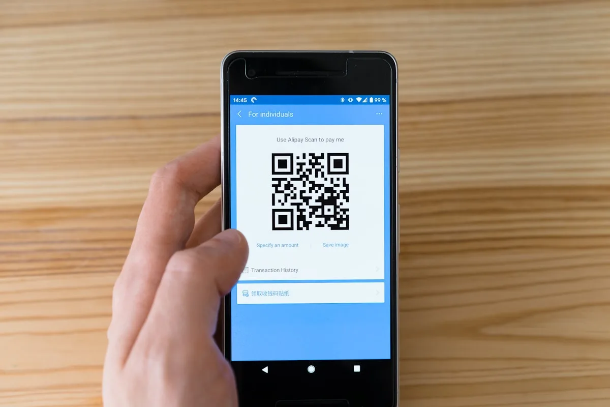 A hand holding a phone showing an Alipay QR code payment screen