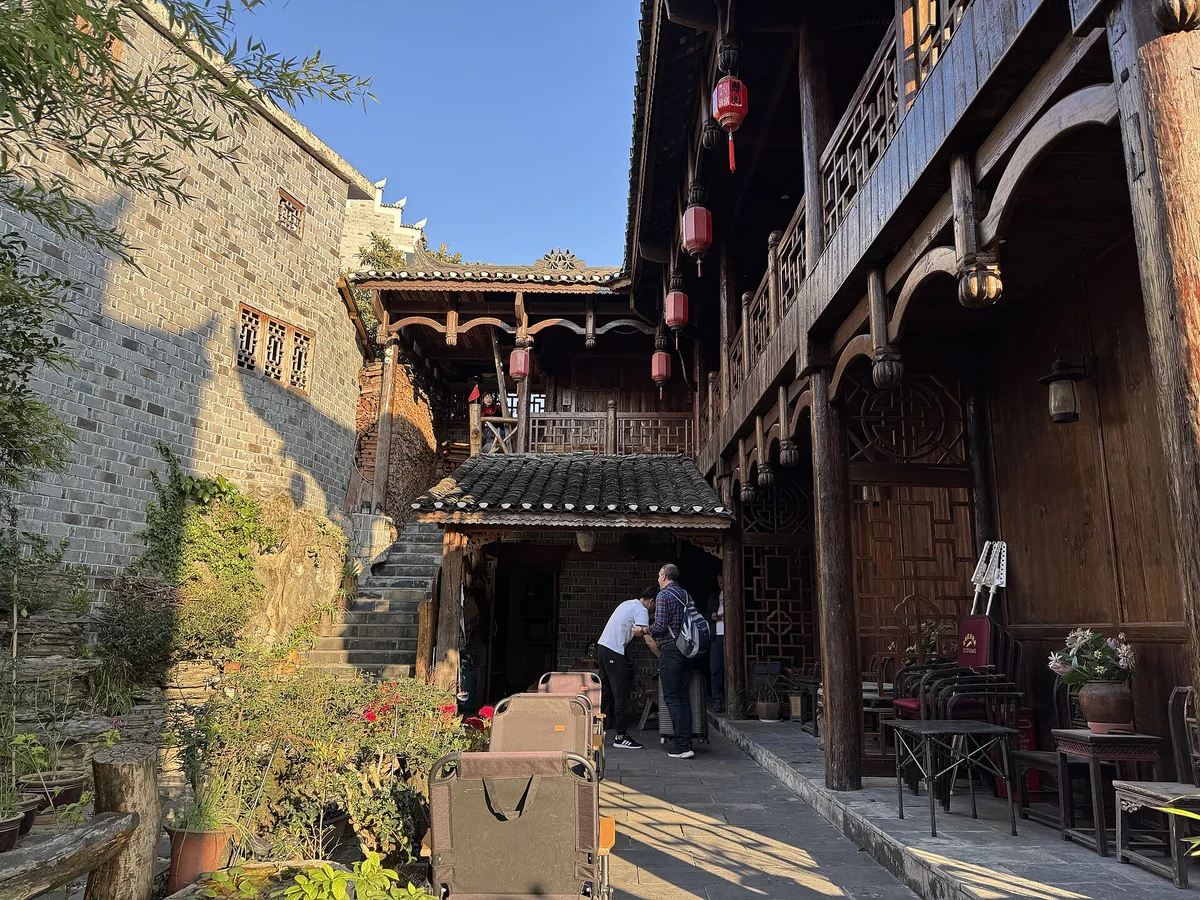 A timber courtyard guesthouse in Furong Town, with carved balconies, red lanterns and stone steps leading up past the entrance (Photo: Codas via Wikimedia Commons)