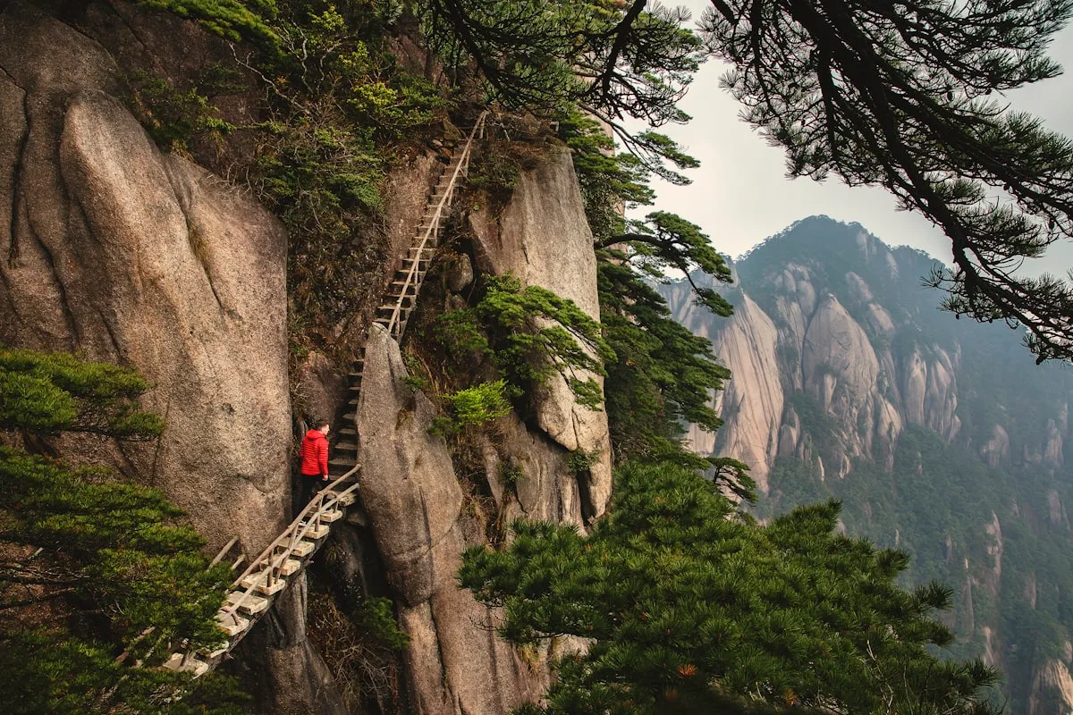 Huangshan's West Sea Grand Canyon, steep stone staircases carved into near-vertical granite cliffs, mist swirling through the gorge below