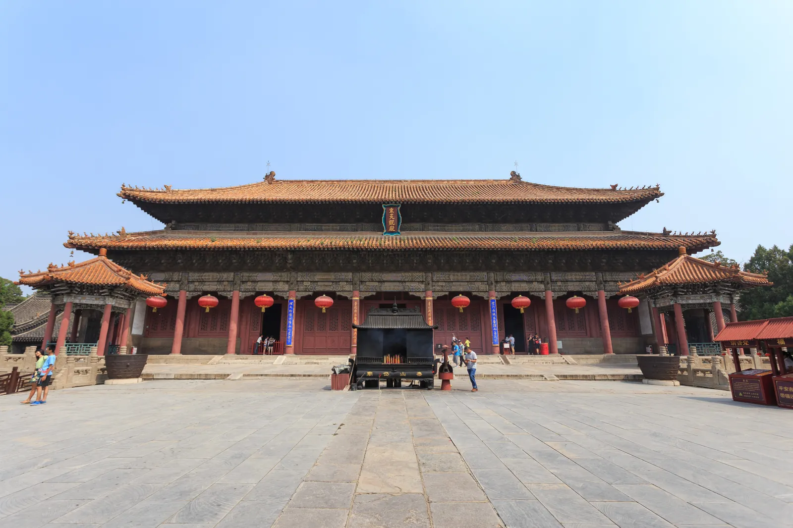 The main hall of the Dai Temple in Tai'an, a wide red and grey timber hall on a raised stone platform under a clear sky (Photo: Zhangzhugang via Wikimedia Commons)