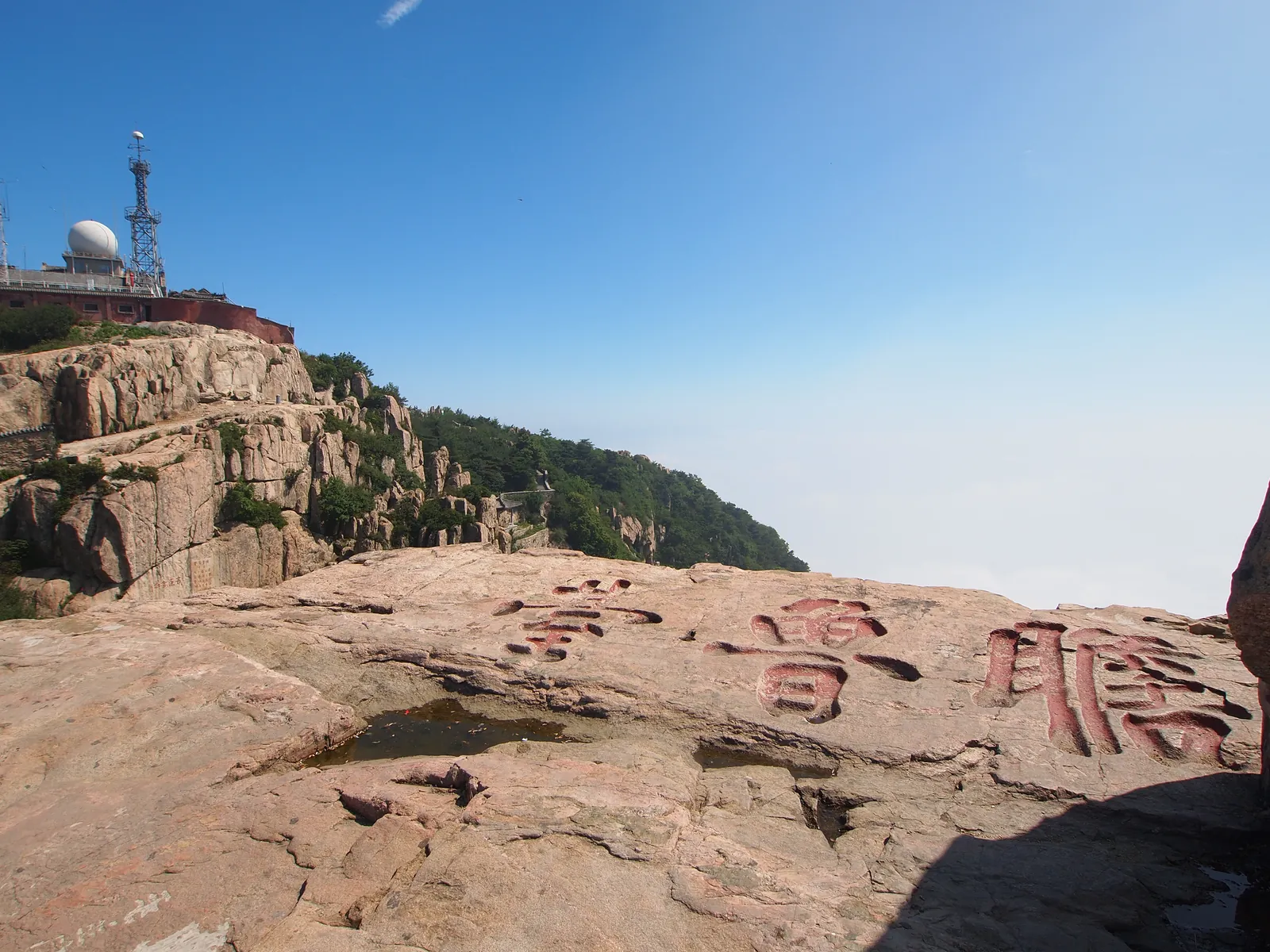 The flat granite shelf of Zhanlu Terrace on the summit of Mount Tai, with its name carved in large red characters into the rock and the observatory dome on the ridge behind (Photo: rheins via Wikimedia Commons)