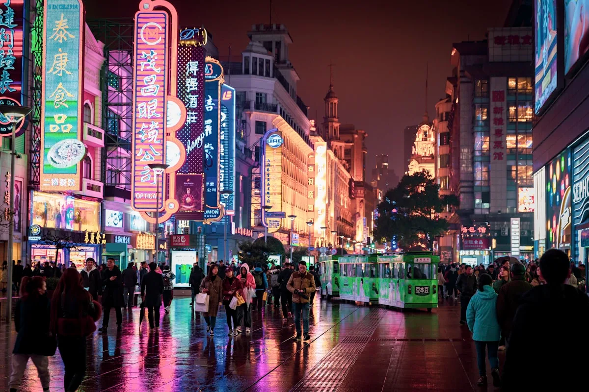 Una calle comercial de Shanghái iluminada con neones, llena de peatones por la noche tras la lluvia