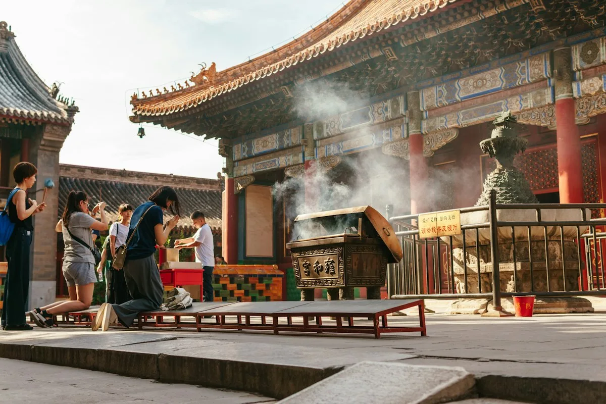 Families burning incense and bowing in the courtyard of a Chinese temple