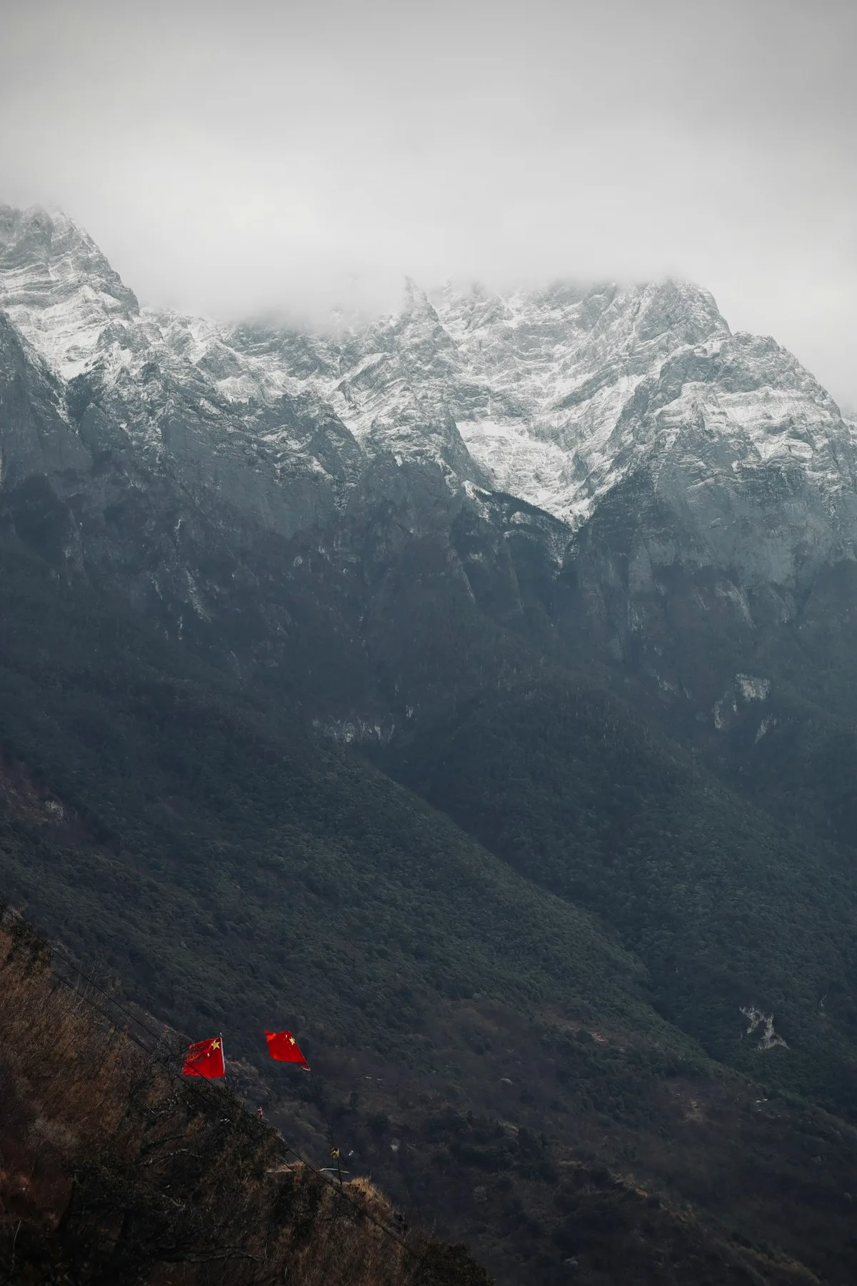 The High Trail at Tiger Leaping Gorge, a narrow path suspended between Jade Dragon Snow Mountain and Haba Snow Mountain, with prayer flags against snow-capped peaks