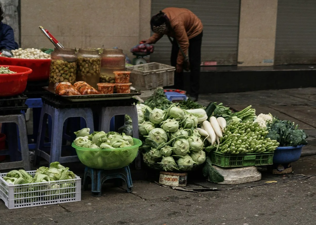 A street vegetable stall in China with cabbage, radish and jars of pickles arranged for sale