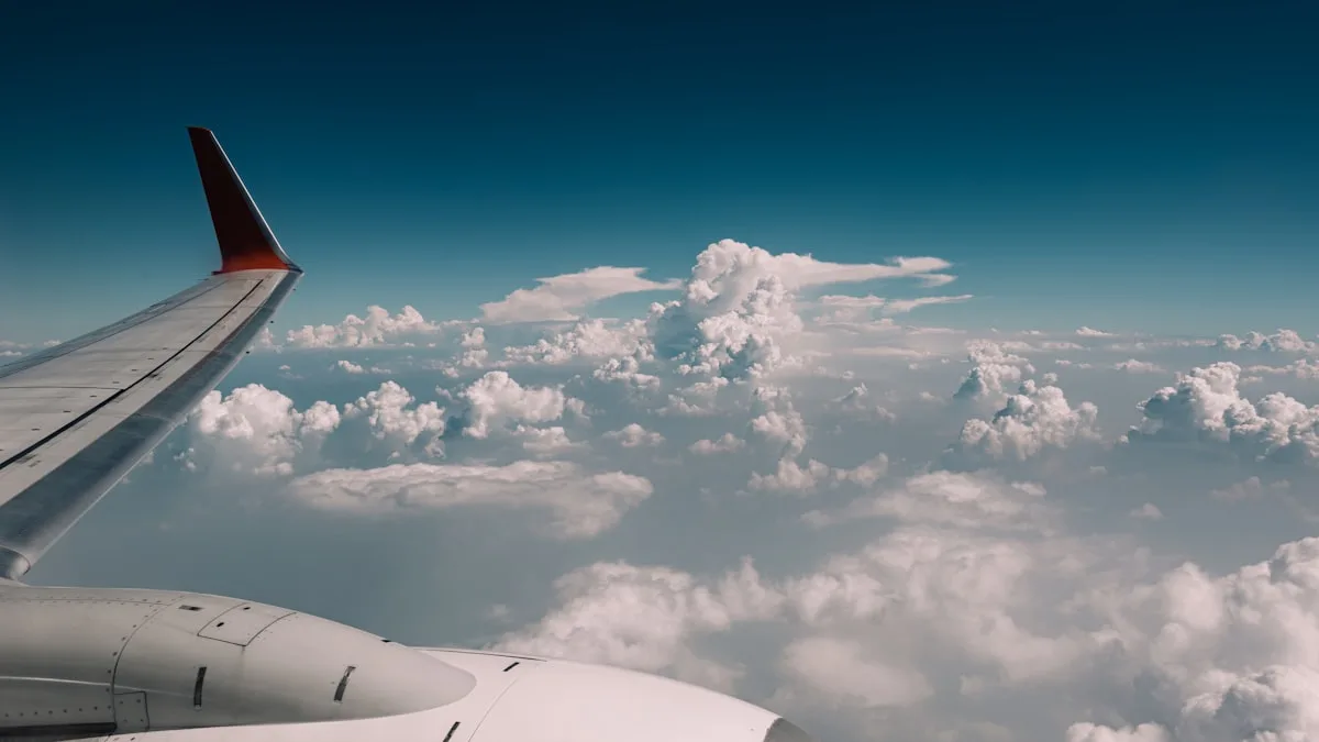 L'aile d'un avion en vol au-dessus d'une couche de nuages blancs, vue depuis un hublot