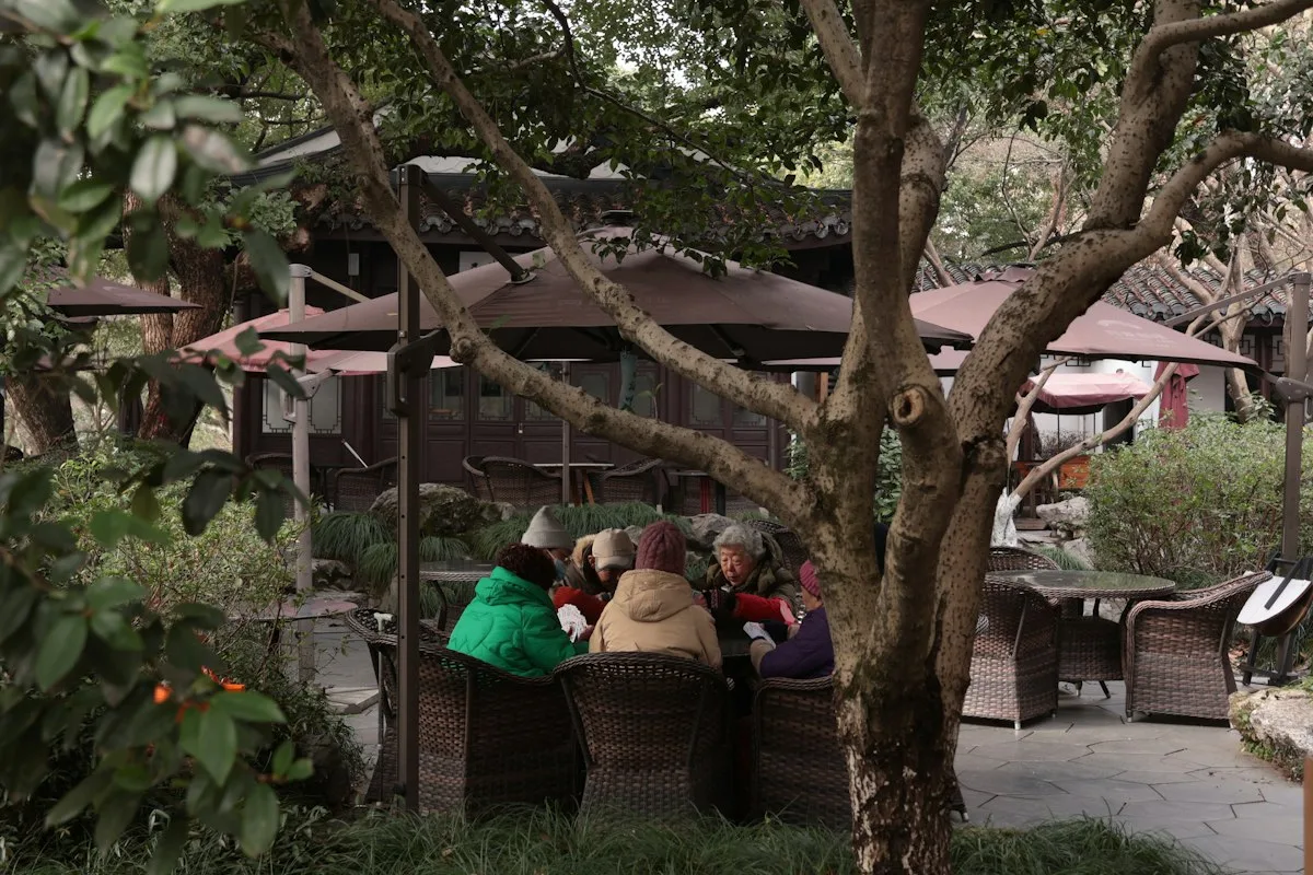 A group of people sitting together in a Chinese courtyard under a traditional wooden structure