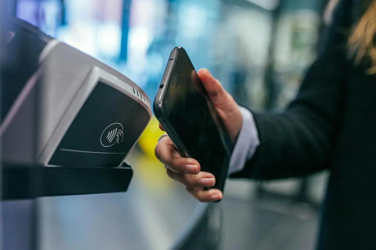 Une personne approchant un smartphone d'un terminal de paiement sans contact