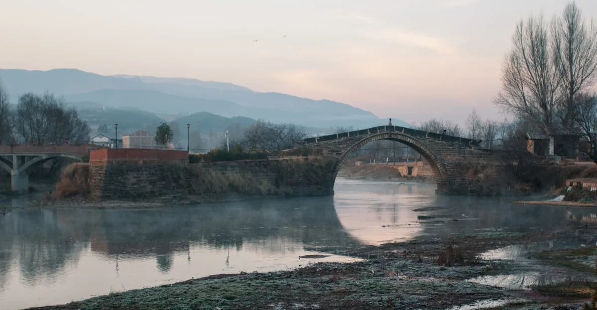 puente de arco gris con vista a la montaña bajo cielo blanco y azul