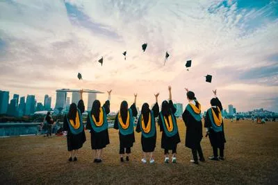 Graduates in caps and gowns throwing their hats in the air, celebrating graduation season