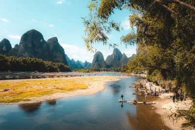 Karst mountains rise above a tranquil river with bamboo trees near Yangshuo