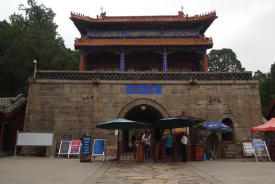 The stone gatehouse of Wanxian Tower on the Red Gate route up Mount Tai, with turnstiles, notice boards and staff at the entrance