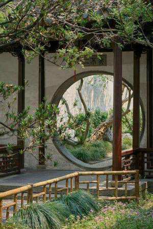 Traditional Chinese garden with circular moon gate reflecting in pond in Suzhou