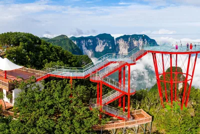 The glass Sky Eye platform and a glass walkway on red steel supports above a sea of clouds, with Zhangjiajie's sandstone pillars behind