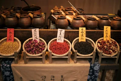 A market stall selling Chinese herbs and tea ingredients in pottery jars and bamboo baskets